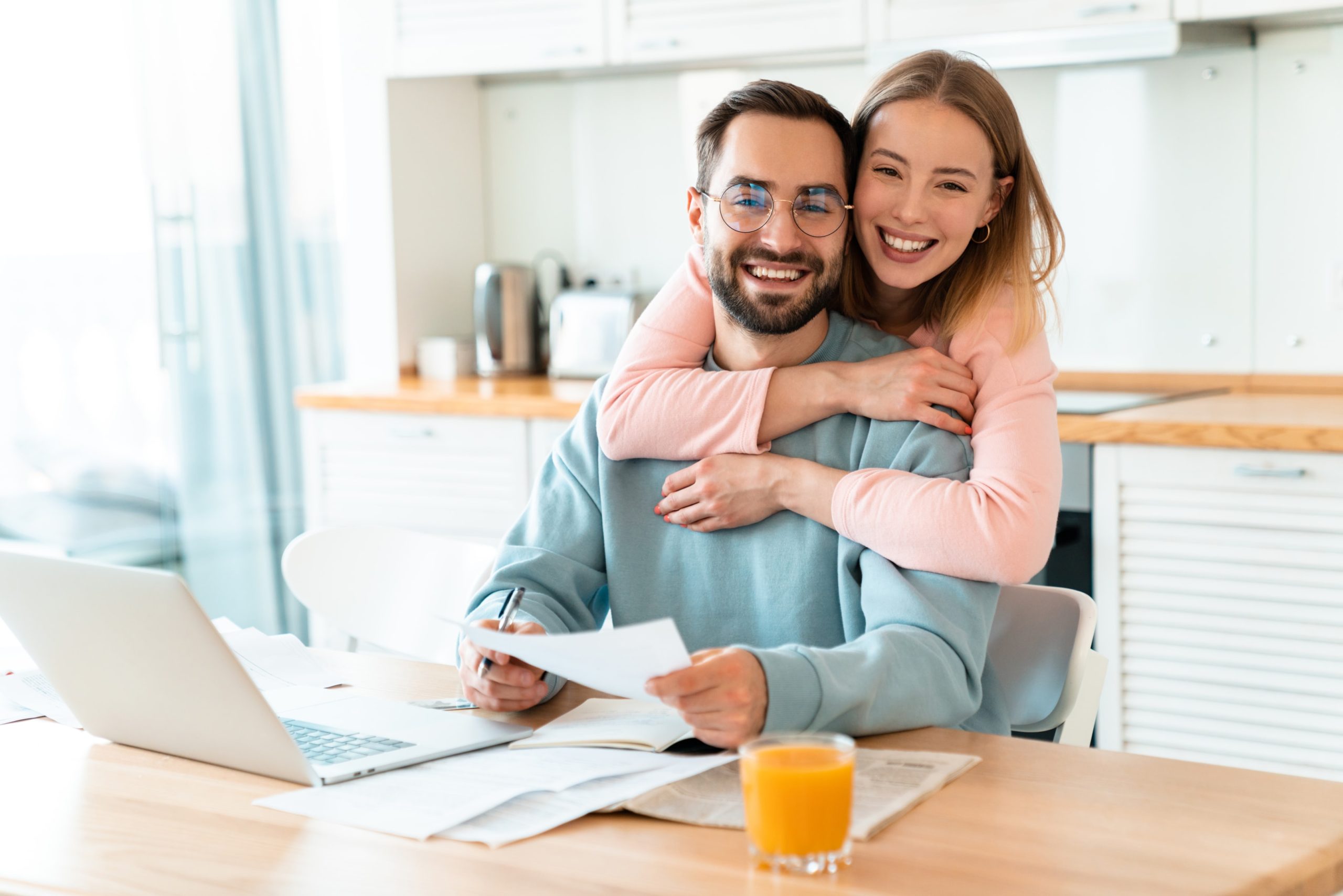 Portrait of smiling couple hugging while working with documents