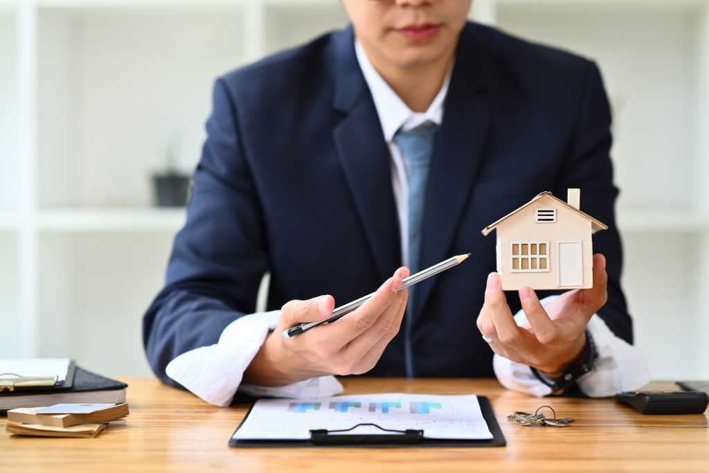 Realtor in black suit hand holding house model. Real estate mortgage and property investment concept, buyers, journey, agents tenant, lifestyle queensland, journey agents, process, buyers success, diligence, beach, aspects, builders, matter, proximity, agents leading save, queensland invest