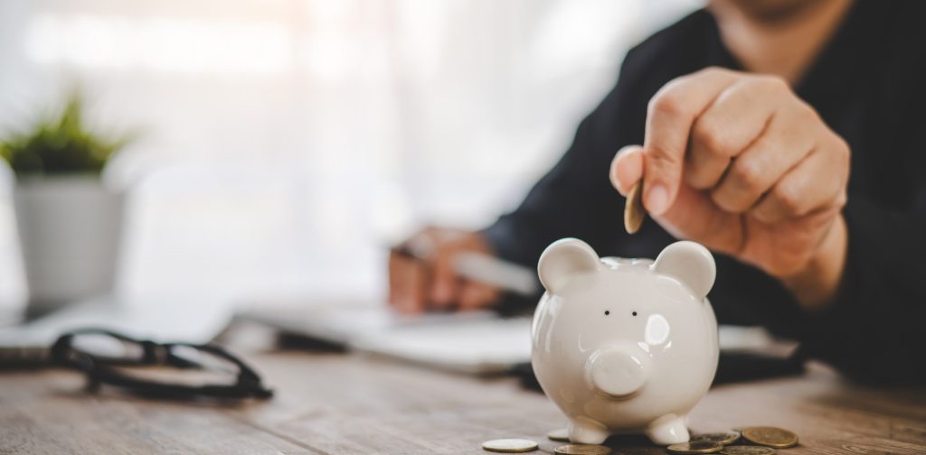 Hand holding coin with pig piggy bank. Saving and financial accounts concept less income tax