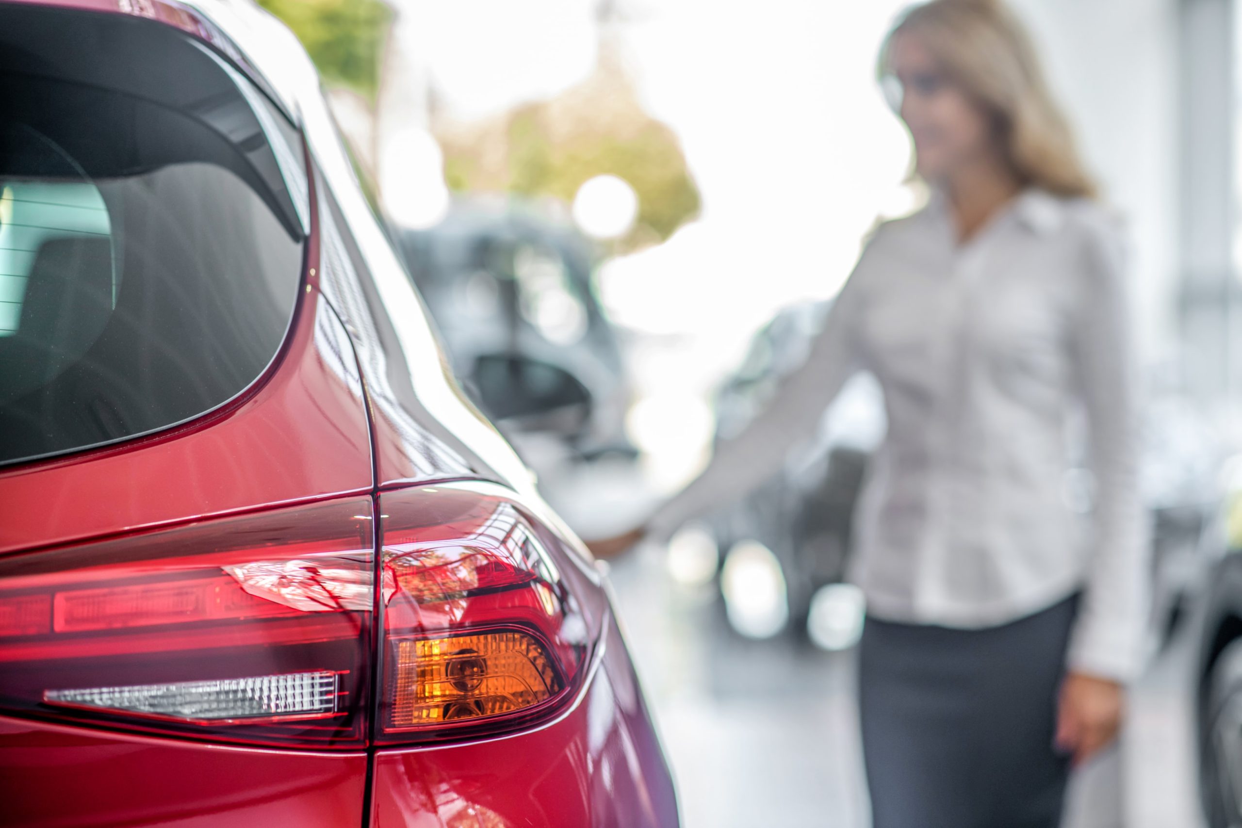 Close-up of a car in a showroom with a person in the background used to illustrate a novated lease calculator for vehicle cost estimates