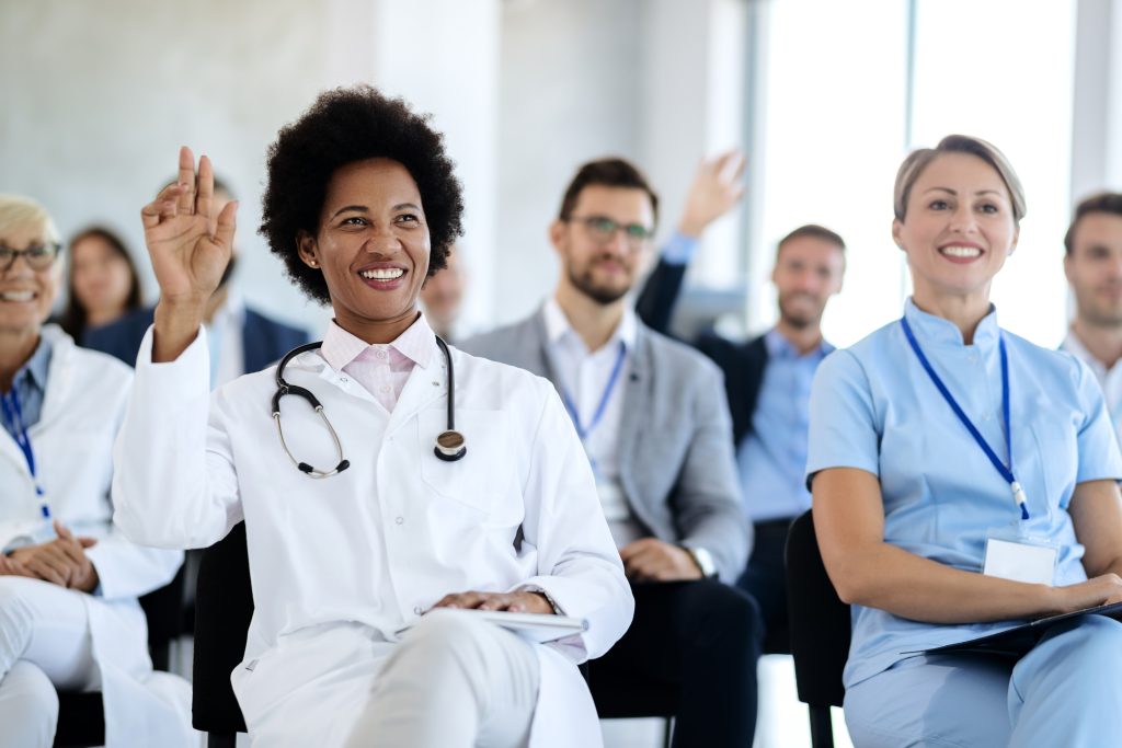 doctor raising her hand to ask a question during a seminar in convention center.