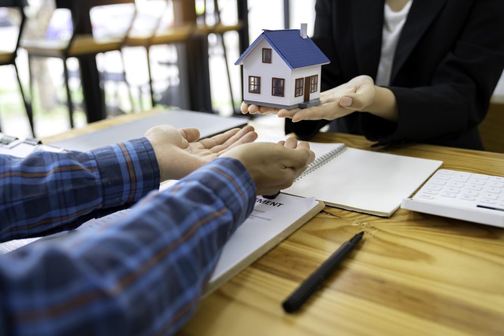 real estate agent salesman holds a model of a house and sends it to customers as an example